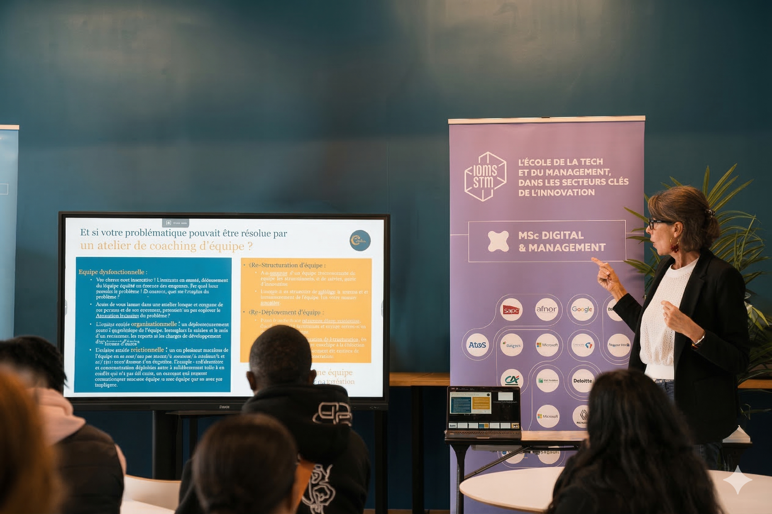 Conférence type workshop avec un ecran, un kakémoni et une conférencière qui pointe sur l'écran