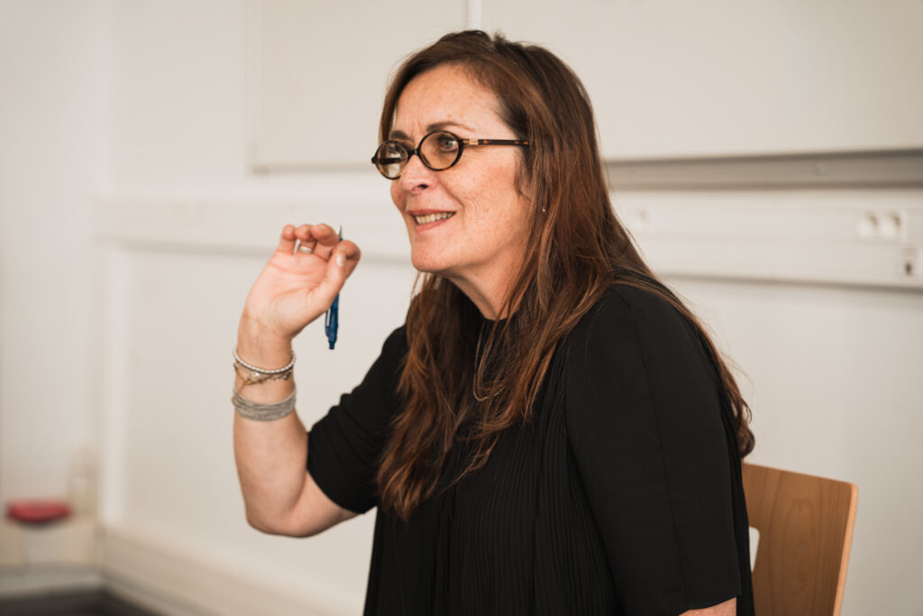 Femme en noir qui explique dans uene salle aux murs blancs